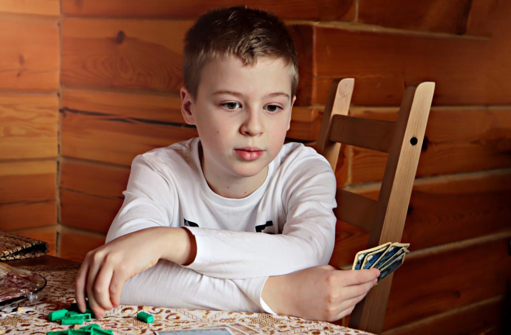 boy holding cards, symbolizing the cards (reasons behind) Outshining AI