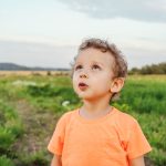 A young boy looks to the sky, quietly awed by its breathtaking beauty.