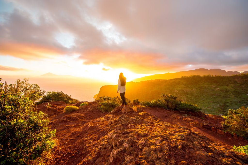 Person standing on a mountain overlook at sunrise, symbolizing the dawn of the AI Age and a new era of technological change.