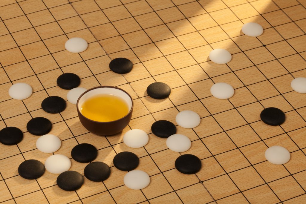 A Go playing board with a cup of liquid on it.